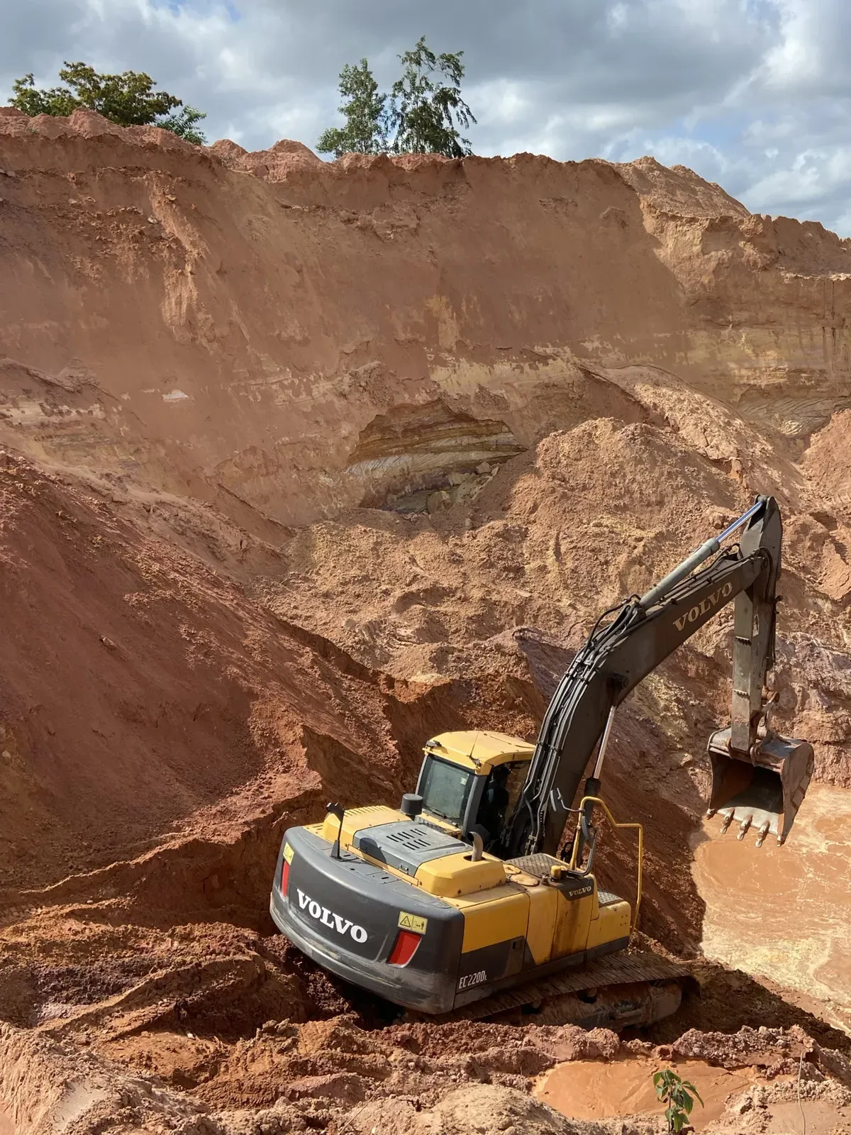 O barranco da jazida em camadas, com a escavadeira trabalhando embaixo