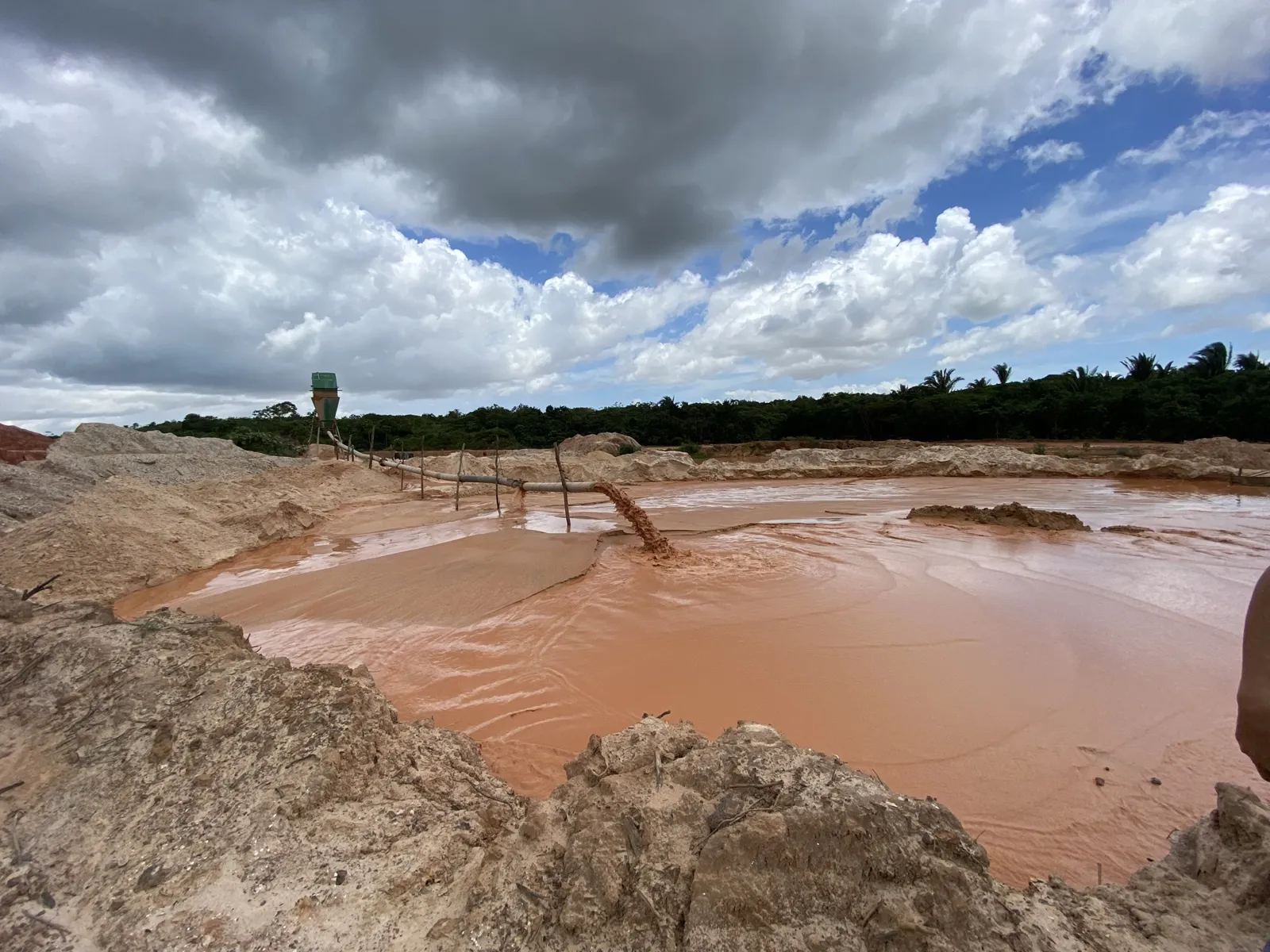 A água da lavagem saindo barrenta na lagoa de decantação da jazida